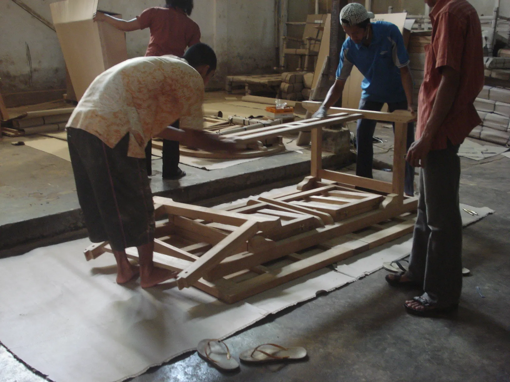 Assemblage de tables en teck en atelier