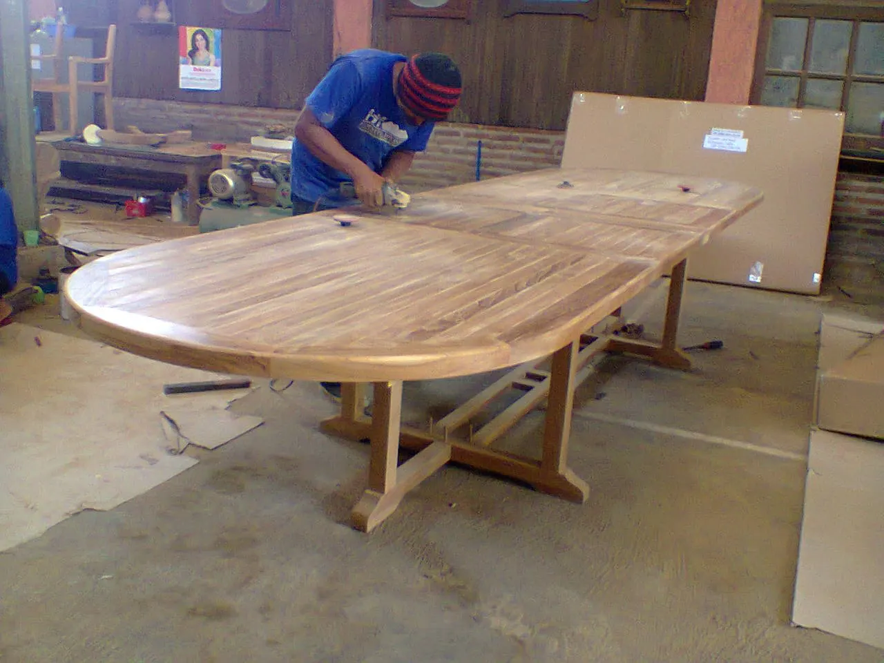 Ponçage de finition d'une table ovale en teck