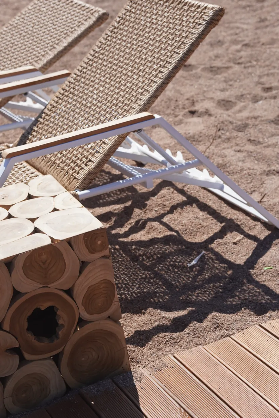 Transats alignés sur le sable, au pied du deck