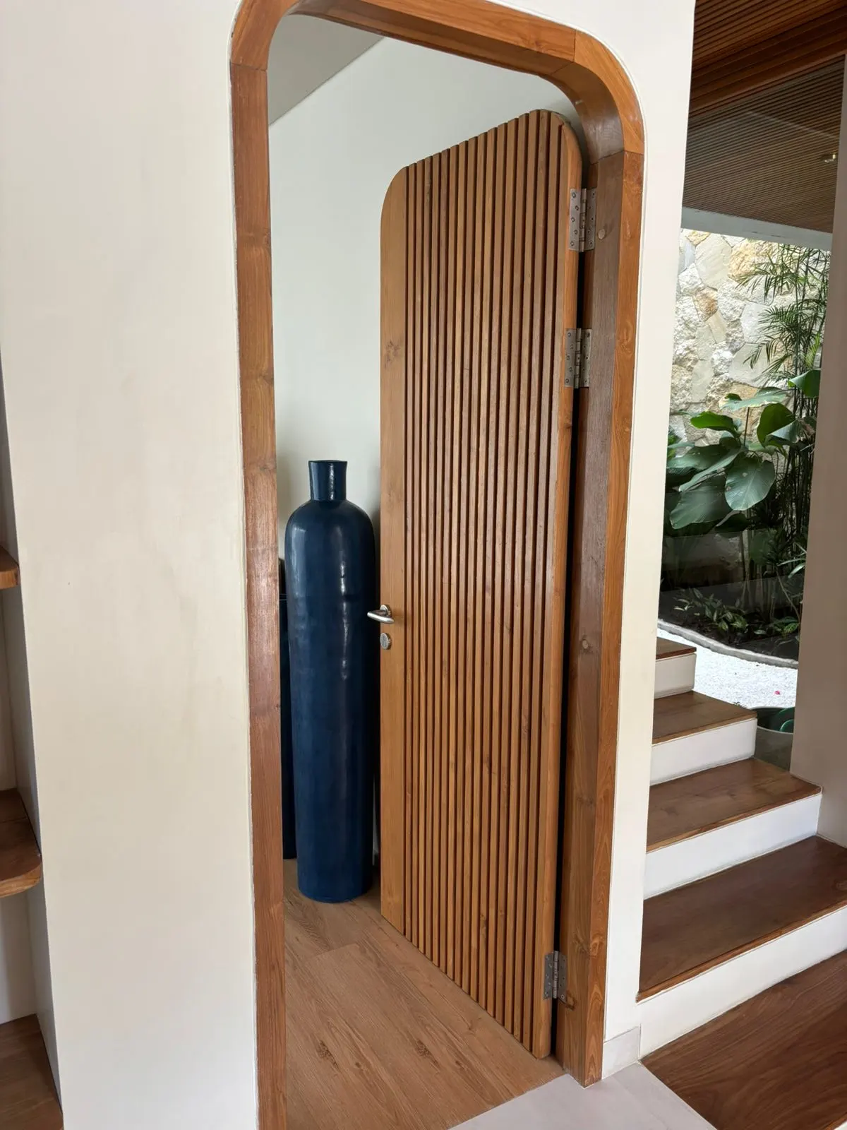 Porte cintrée à lames en teck, posée dans une villa
