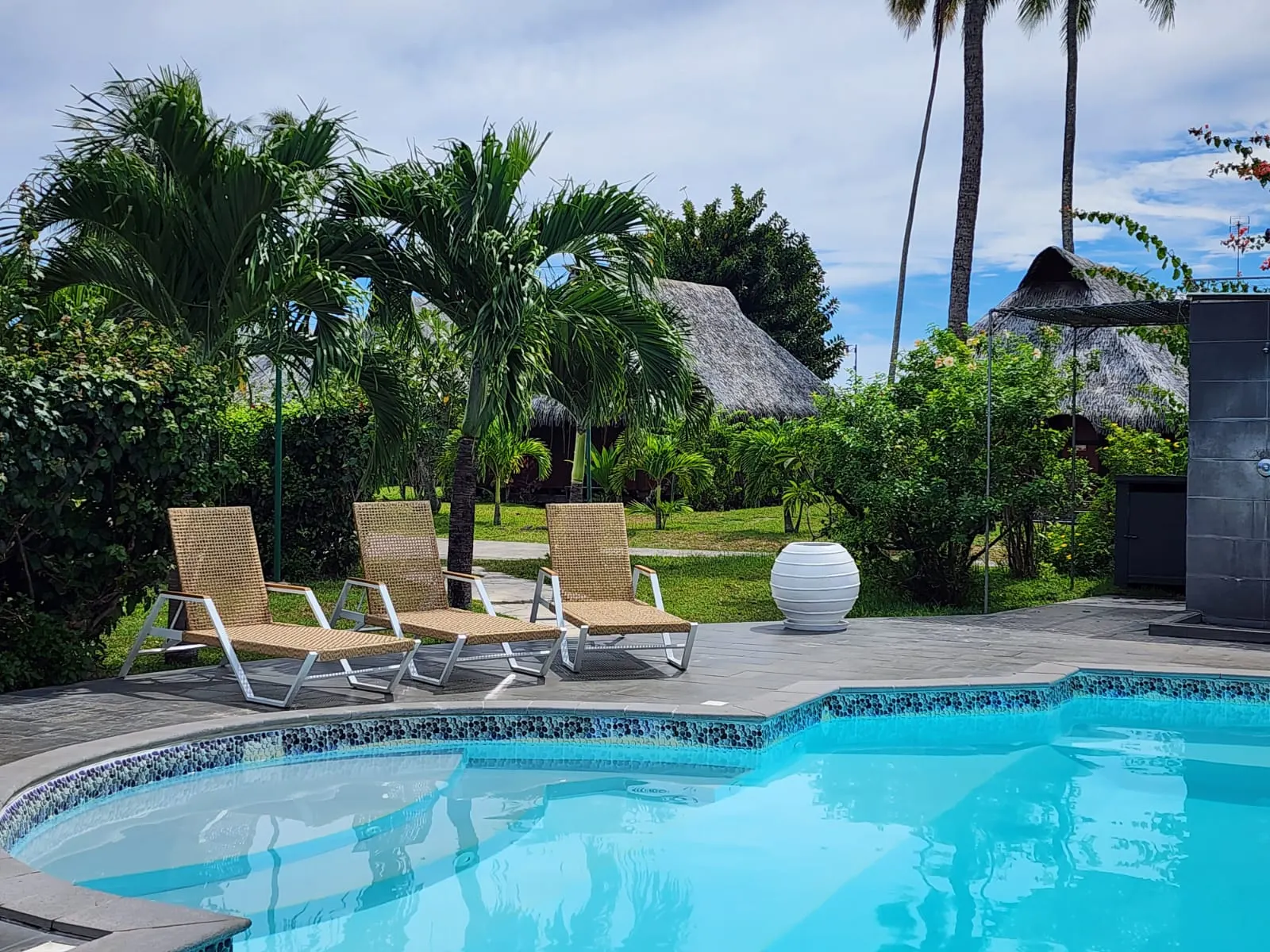 Bains de soleil en cannage tressé, bungalows à toit de pandanus